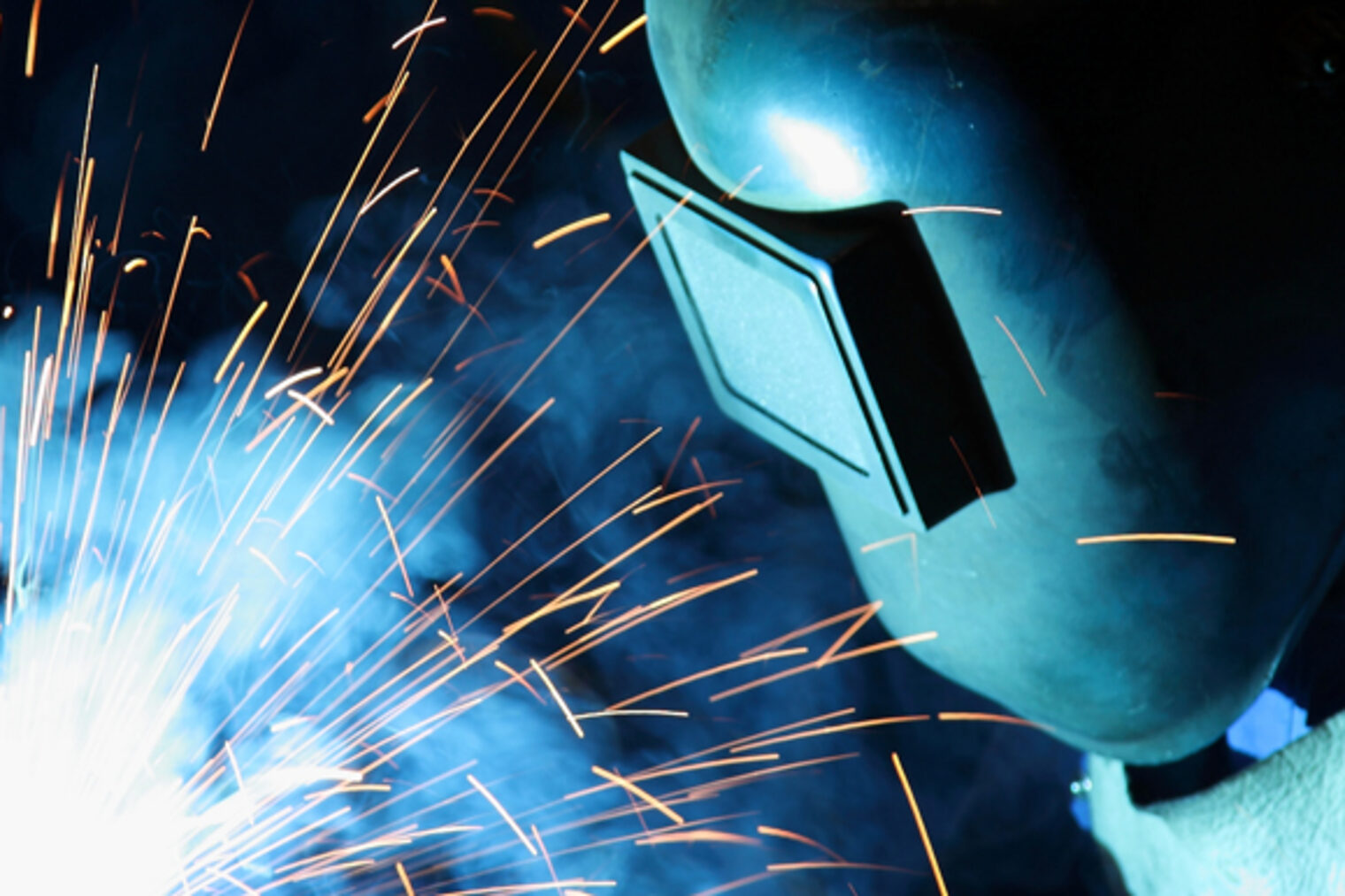 Handwerker mit einer Arbeitsschutzmaske schweißt an einem Metallstück.
