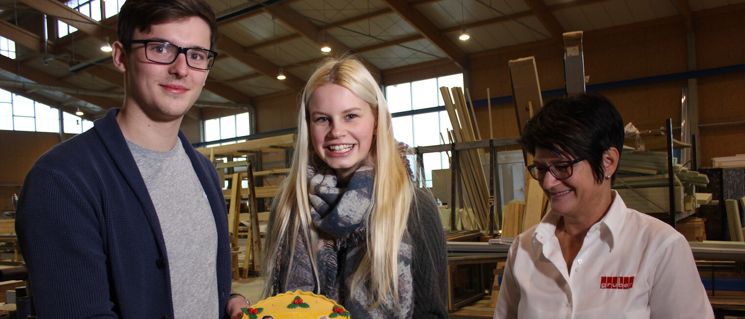 Am letzten Tag ihres Rekordpraktikums durften sich Charlotte (Bildmitte) und Marvin über eine Torte freuen, mit der sie die Personalreferentin der Firma Gruber Holzhaus, Johanna Gruber (rechts) und die Handwerkskammer Niederbayern-Oberpfalz überraschten. 