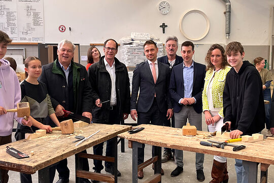 Besuchten die Schüler in der Werkstatt: HWK-Vizepräsident Gerhard Ulm (3. v.li.), Schulleiter Bernhard Schiffer (5. v.li.), Mario Göhring, stellvertretender Abteilungsleiter Betriebsberatung (Mitte), Linda Kraus, Koordinatorin für Berufsorientierung (2. v. re.) und Kreishandwerksmeister Michael Berchtold (re.). 