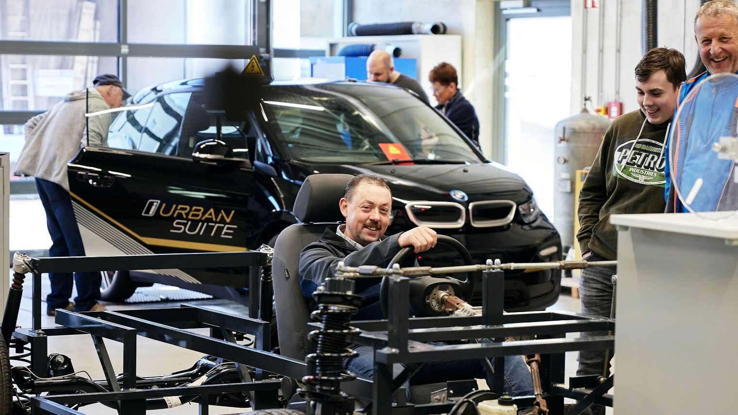 Besucher in der Kfz-Werkstätte. Mann sitzt in einem Auto. 