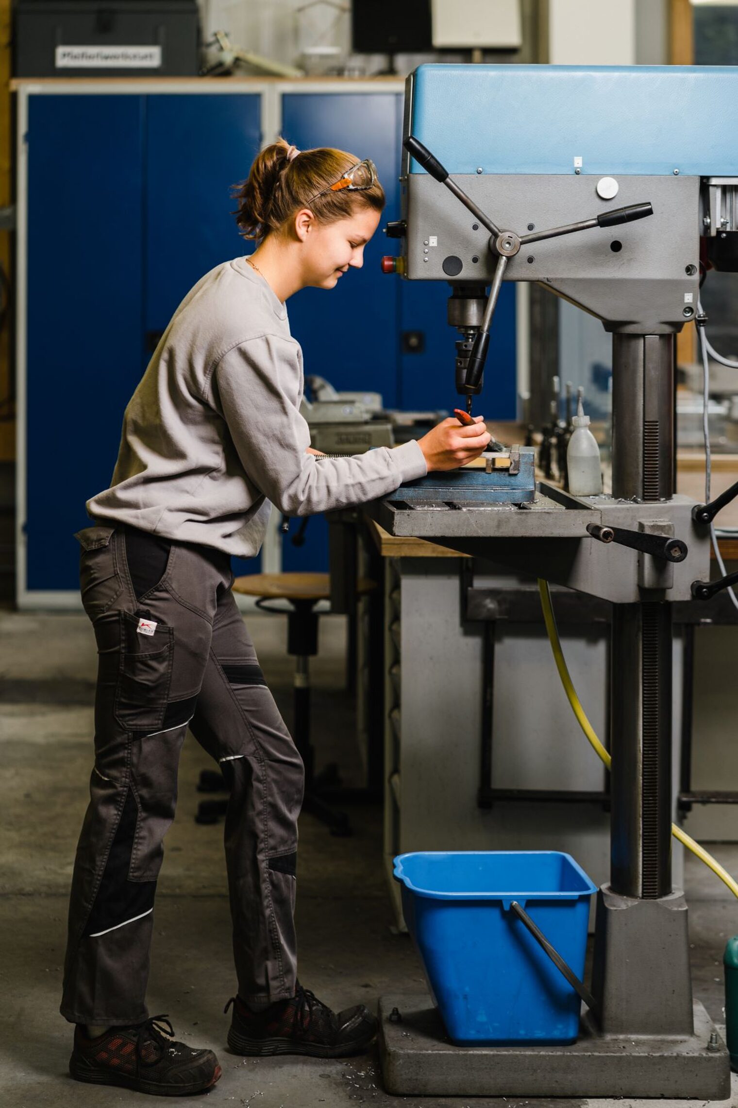 Metallbauerin Sophie Parstorfer steht an einer Fräsmaschine und bearbeitet ein Teil. 