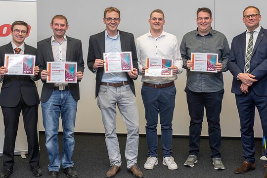 Die Gewinner stehen in einer Reihe und halten ihre Urkunden in den Händen. 