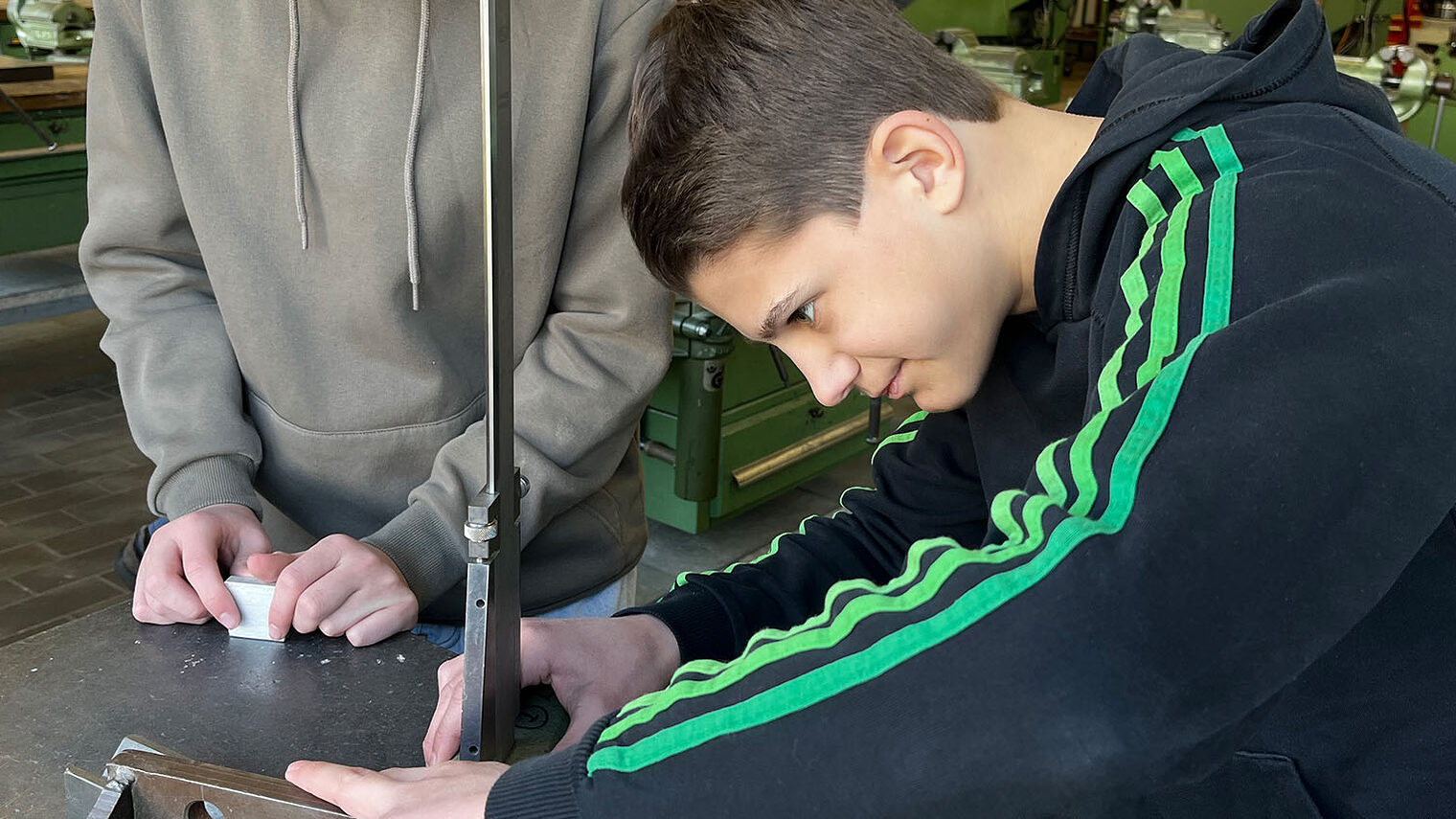 Zwei Schüler feilen an einem Metallobjekt. 