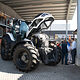 Die Motorhaube des Traktors der Innung für Land- & Baumaschinentechnik wurde geöffnet, einige Menschen stehen interessiert daneben. 
