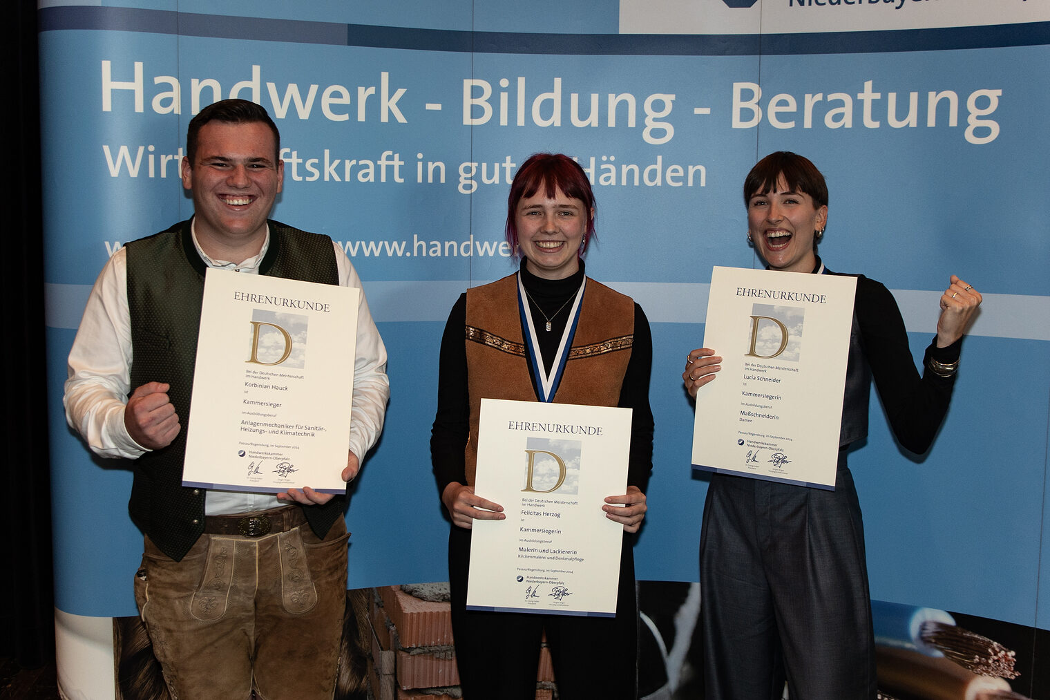 Drei der besten Gesellen Ostbayerns halten ihre Urkunden hoch und freuen sich über ihre Topleistungen bei der „Deutschen Meisterschaft im Handwerk“.