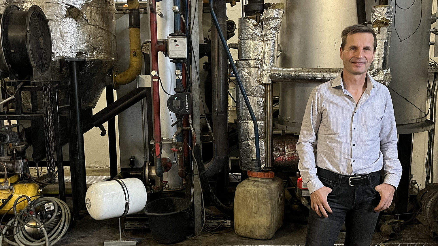 Michael Artmann steht stolz vor seinem Reaktor, bei dem hochreines, nachhaltiges Holzgas entsteht.