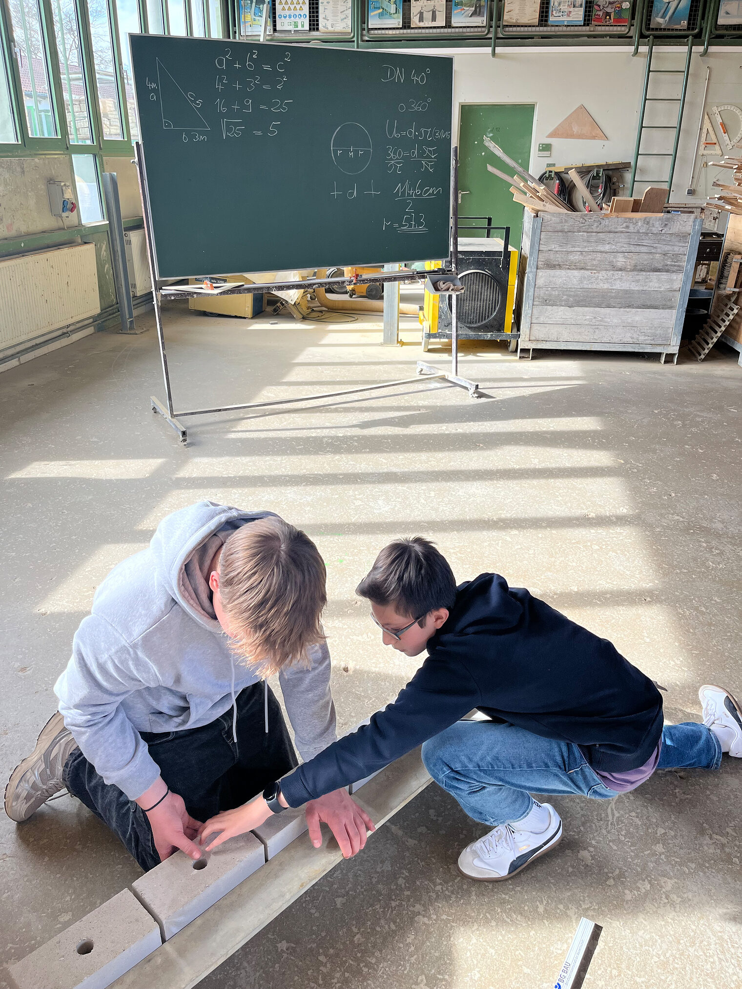 Zwei Schüler durften auf einer Tafel Berechnungen erstellen und anschließend das Mauerwerk im Trockenverband fertigen. 