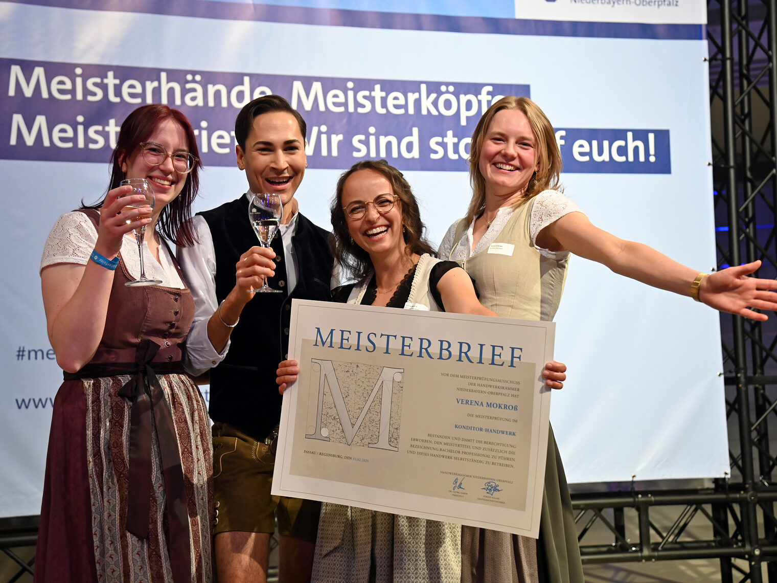 Ein Hoch auf die neuen Meister: bei der Verleihung der Meisterbriefe herrschte ausgelassene Stimmung. Eine Meisterin lässt sich von ihren Freunden vor der Bilderwand feiern.