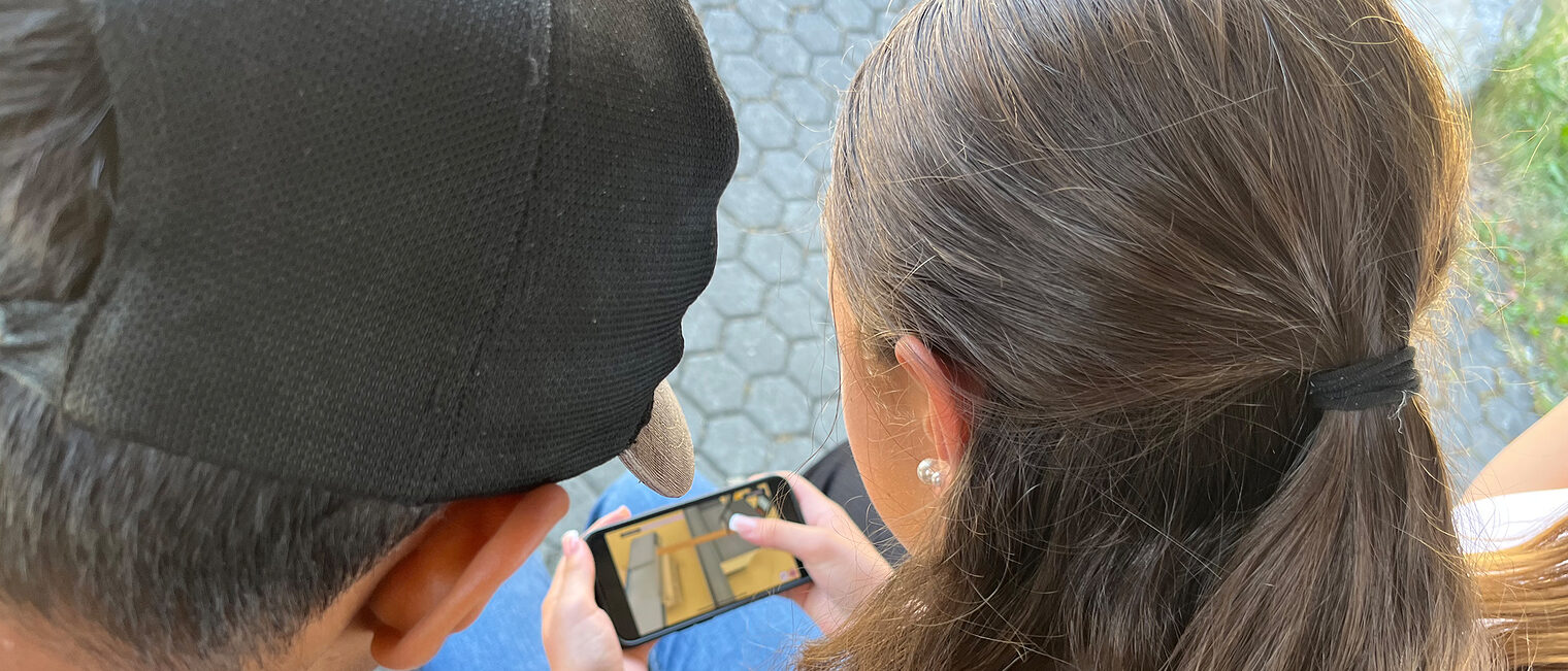 Nah an der Praxis: das virtuelle Praktikum bringt Jugendlichen den Beruf des Schreiners näher und das bequem übers Smartphone. Zwei Jugendliche spielen das virtuelle Praktikum auf einem Smartphone.