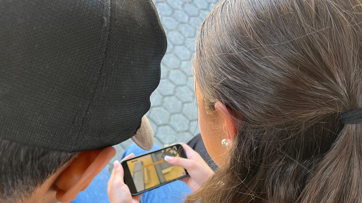 Zwei Jugendliche spielen das virtuelle Praktikum auf einem Smartphone. 