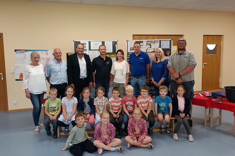 Die Kinder des Gemeindekindergartens Oberdietfurt posieren mit mehreren Erwachsenen und der HWK-Vizepräsidentin Claudia Geiselhöringer in einem Raum.