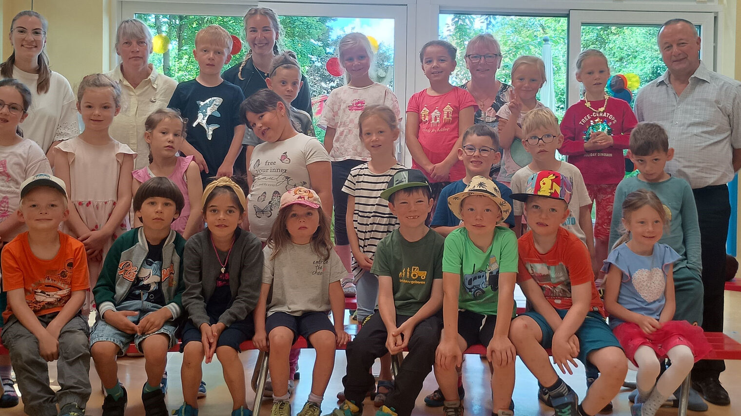 Die Kindergartengruppe, Erwachsene und HWK-Vizepräsident Christian Läpple stehen und sitzen in einem Raum mit großen Fenstern.
