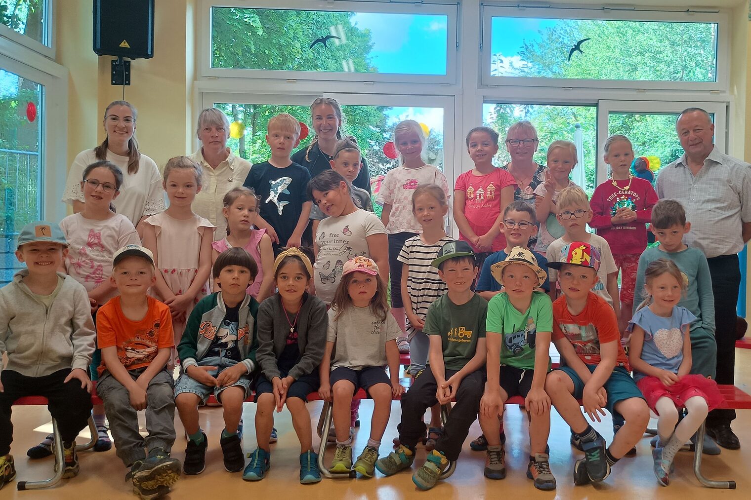 Die Kindergartengruppe, Erwachsene und HWK-Vizepräsident Christian Läpple stehen und sitzen in einem Raum mit großen Fenstern.