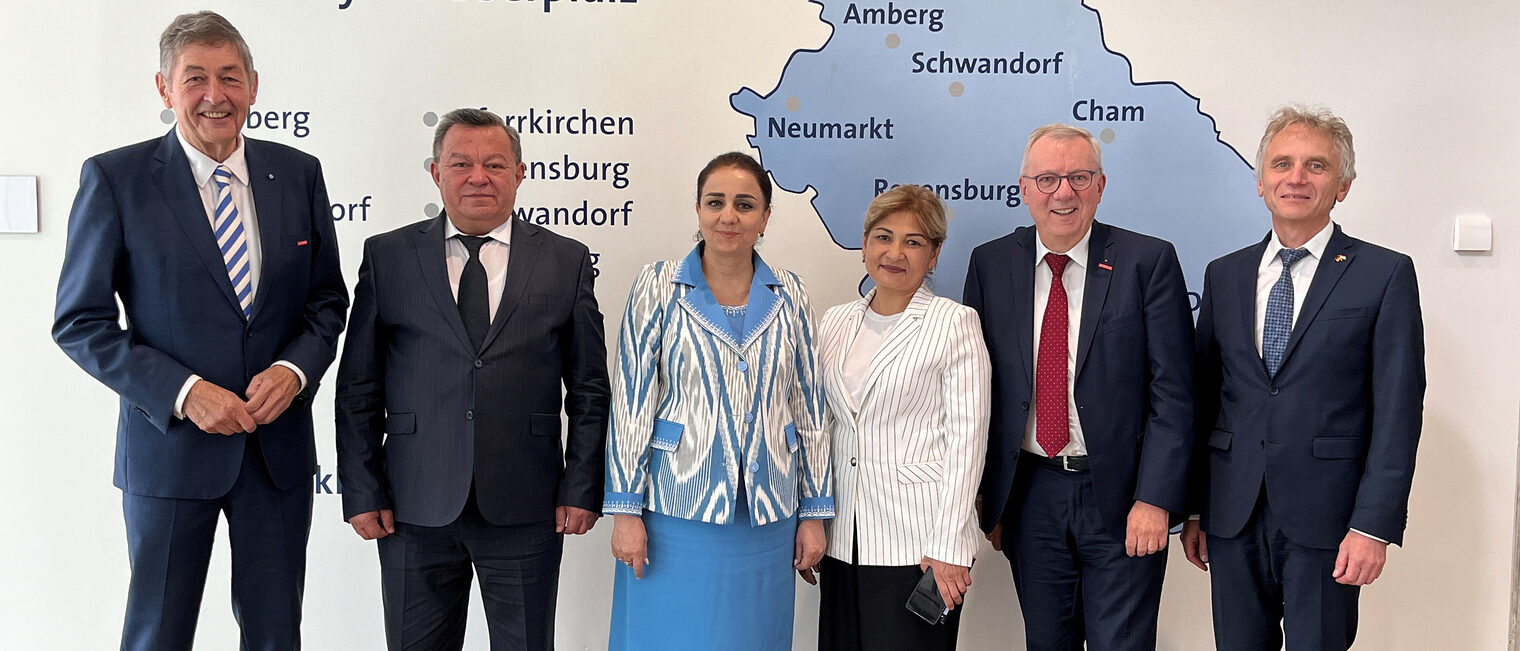 Sechs Personen, darunter Vertreter der Handwerkskammer, stehen in formeller Kleidung vor einer Karte der Region Niederbayern-Oberpfalz.