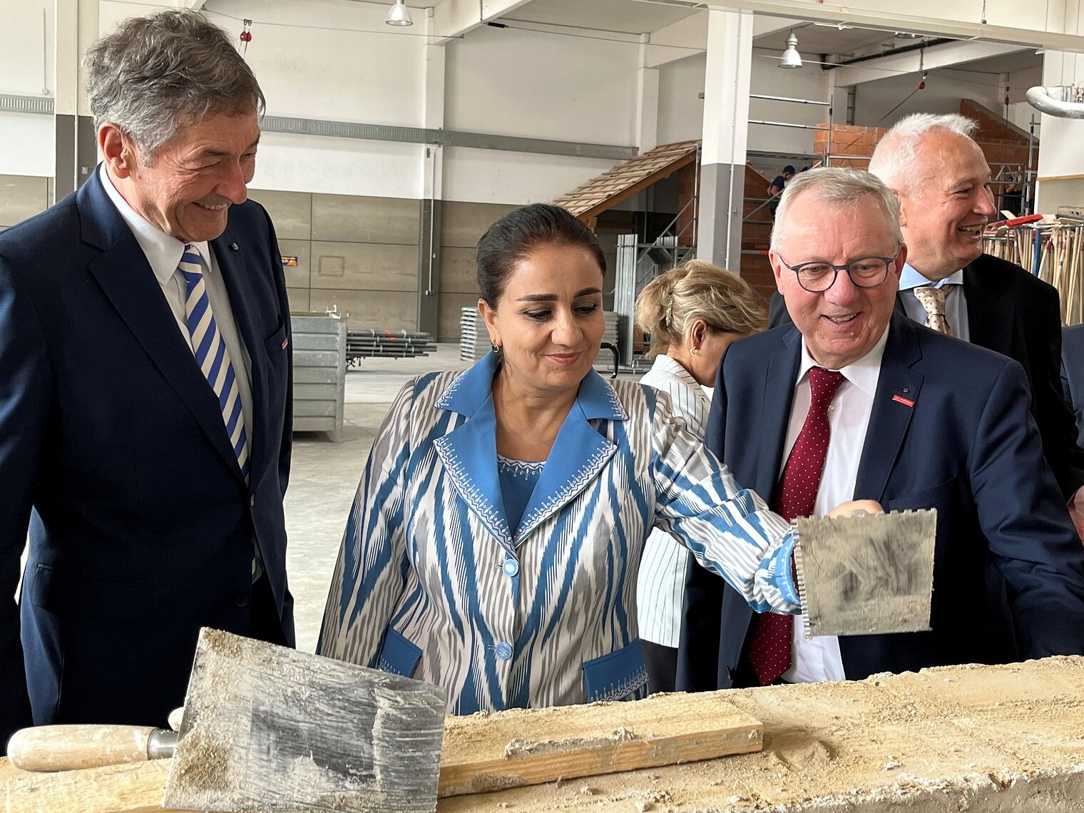 Die beiden Handwerkskammervertreter und die tschikistanische Ministerin mit Maurerkelle in der Hand bei der Besichtigung einer Maurerwerkstatt . 