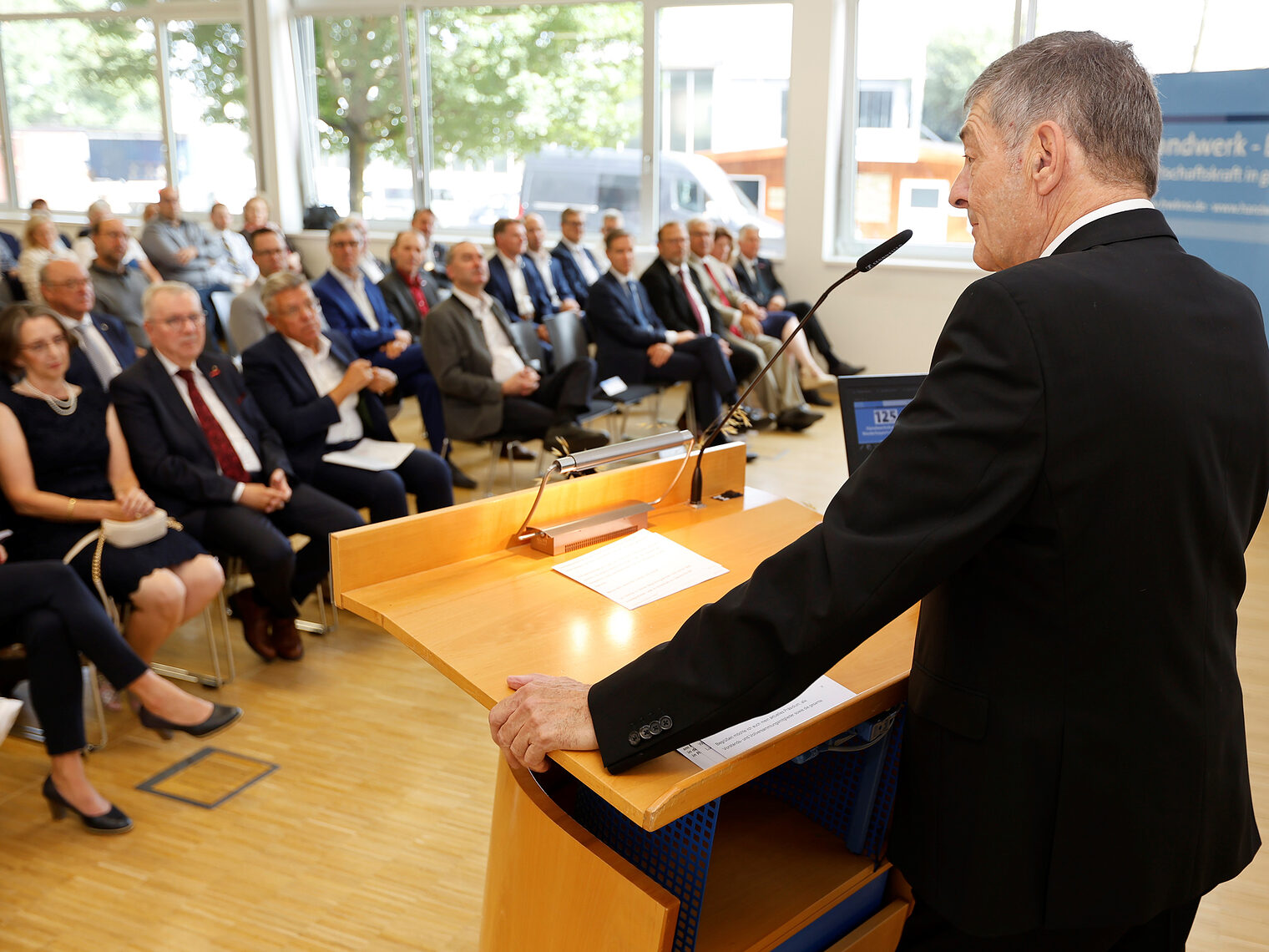 Handwerkskammerpräsident Dr. Georg Haber an seinem Rednerpult. Im Hintergrund sieht man die Besucher des Festaktest zu 125 Jahre Handwerkskammer.