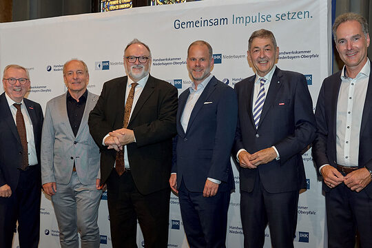 Die Vertreter von IHK und Handwerkskammern stehen vor der Pressewand der IHK Niederbayern und platzieren sich für ein Foto. 