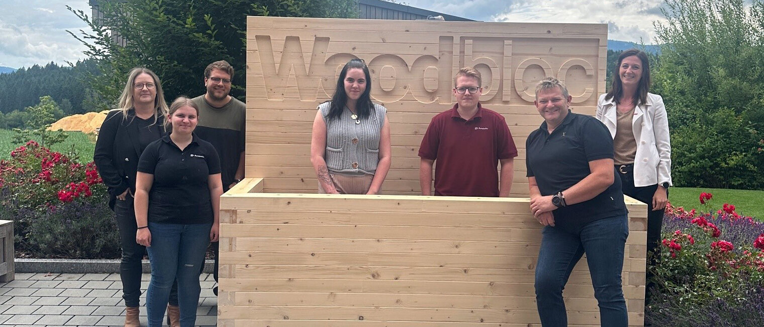 Die Auszubildenden der Firma Penzkofer Bau GmbH haben ein komplett aus Holz gefertigtes Hochbeet gebaut. Für das Foto posieren sie darin.