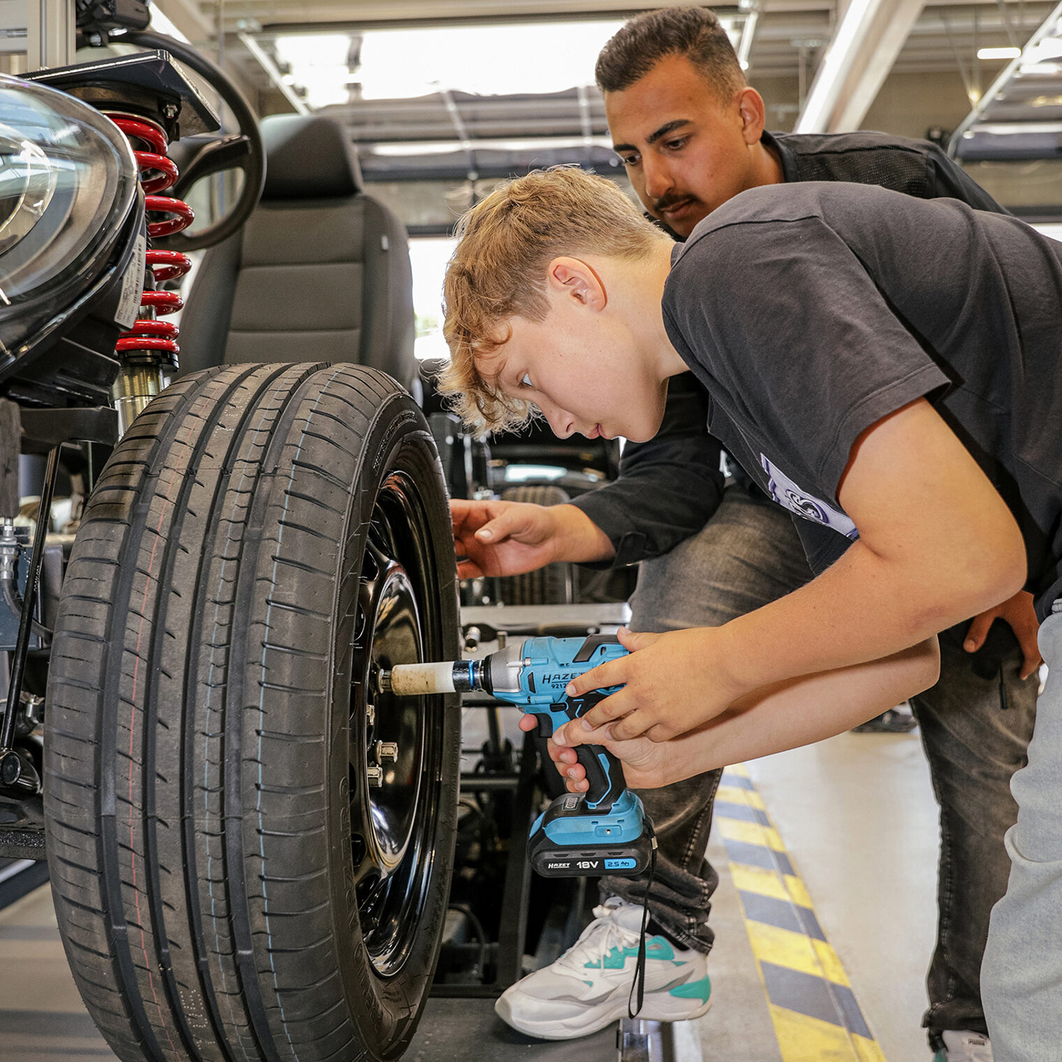 Ein Jugendlicher wechselt einen Autoreifen - und testet so das KFZ-Handwerk.