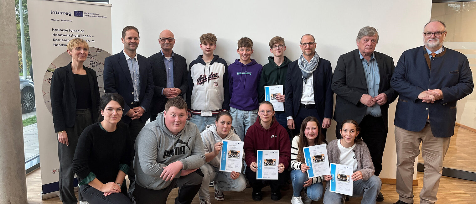 Die Teilnehmer der Sportmittelschule Hauzenberg mit den Projektverantwortlichen. Die Teilnehmer der Sportmittelschule Hauzenberg halten Urkunden hoch. Die Organisatioren des Schüleraustauschs sind auch auf dem Bild.