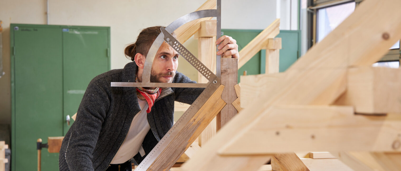 Zimmerer beim ausmessen des richtigen Winkels.
