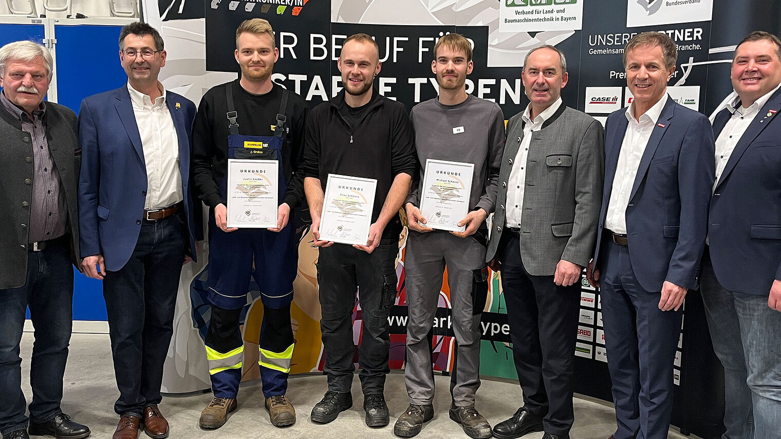 Die drei Bundessieger halten Stolz ihre Urkunden in die Kamera. Auf dem Foto sind sie mit Ehrengästen und Veranstaltern zu sehen.