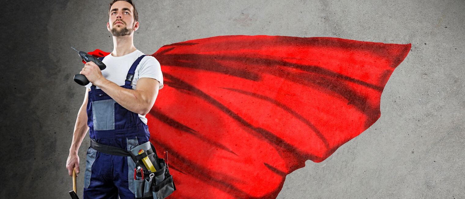 Ein Handwerker steht stolz mit seinen Werkzeugen, einem Hammer und einer Bohrmaschine, im Bild. Er trägt einen Umhang, wie ein Superheld.
