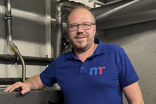 Michael Rädle neben dem „Herzstück“ seines Betriebsgeländes: hier wird Holz in nachhaltige Energie für das gesamte Gewerbegebiet umgewandelt. 