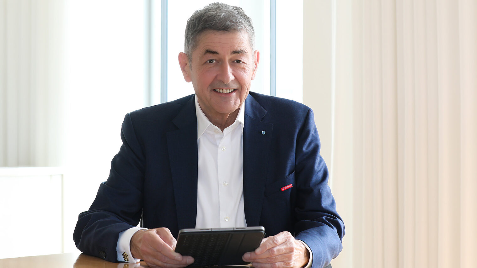 Im Gespräch mit Präsident Dr. Georg Haber. Er sitzt in seinem Büro und hält ein Tablet in der Hand.