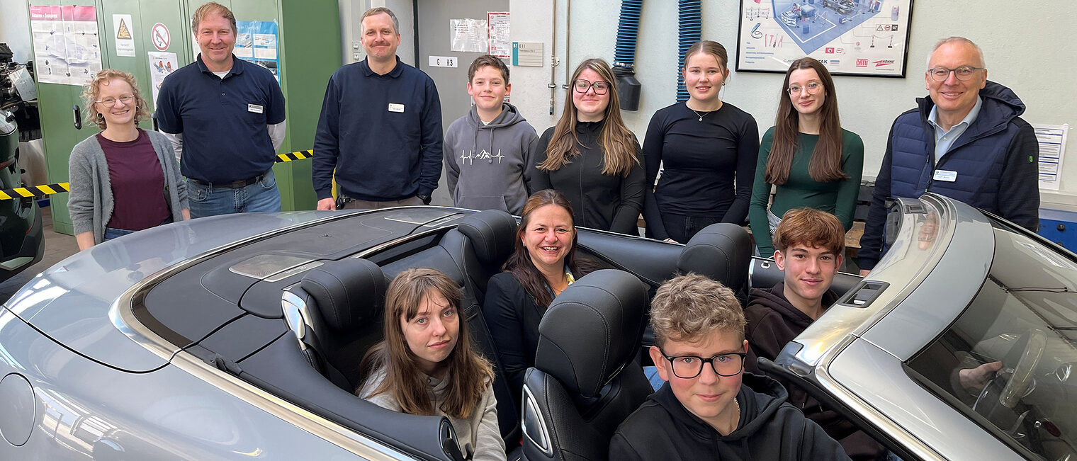 Schüler des Gymnasiums Niederalteich mit Vertretern der Handwerkskammer. Vier davon sitzen in einem Cabrio in der KFZ-Werkstatt.