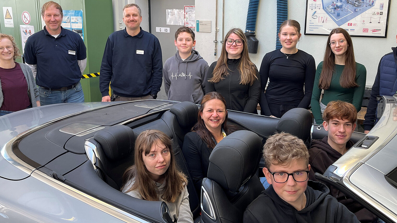 Schüler des Gymnasiums Niederalteich mit Vertretern der Handwerkskammer. Vier davon sitzen in einem Cabrio in der KFZ-Werkstatt.