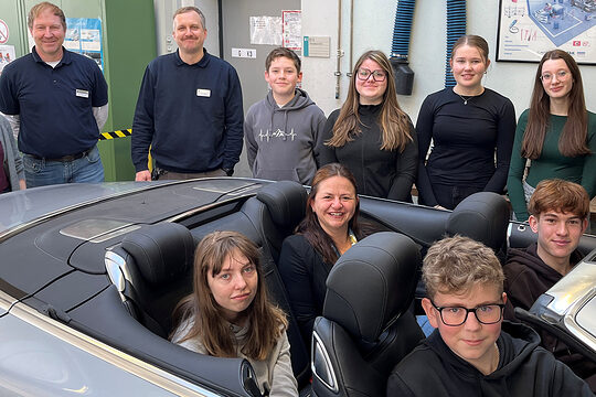 Schüler des Gymnasiums Niederalteich mit Vertretern der Handwerkskammer. Vier davon sitzen in einem Cabrio in der KFZ-Werkstatt.