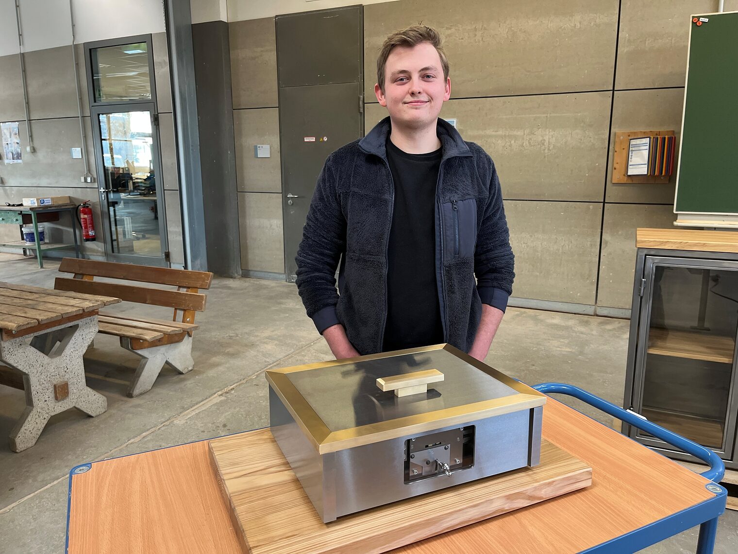 Kursbester Felix Nauruschat steht in der Metallhalle hinter seinem Meisterstück: einer hochwertigen Dokumentenkassette. 