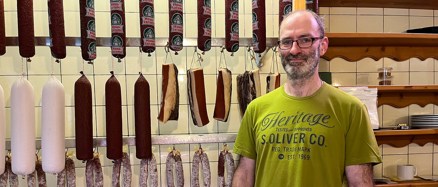 Metzgermeister Winfried Hartmanns präsentiert sich in seinem Laden vor der Wursttheke. 