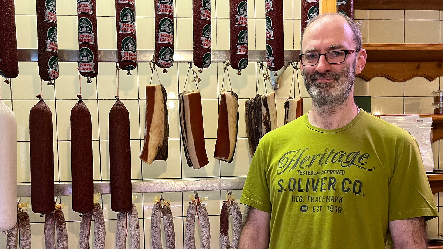 Metzgermeister Winfried Hartmanns präsentiert sich in seinem Laden vor der Wursttheke. 