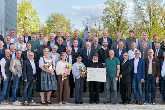 46 Handwerksmeisterinnen und Handwerksmeister mit HWK-Vertretern vor der Handwerkskammer bei der Verleihung der Goldenen Meisterbriefe.