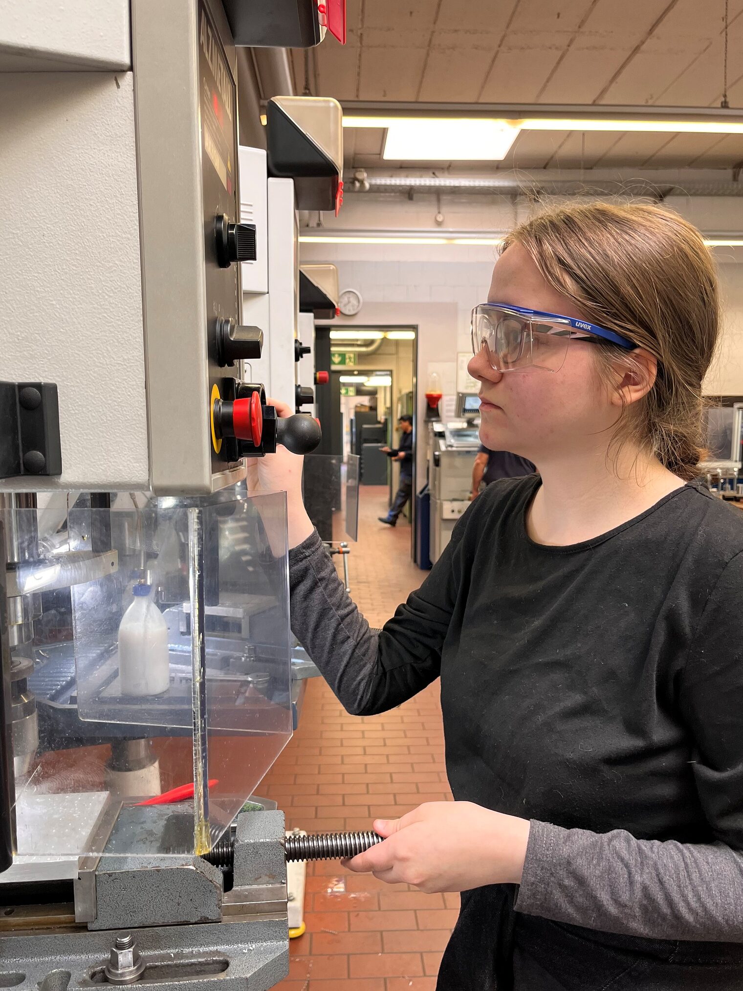 Ein Mädchen mit Schutzbrille bedient eine Maschine in der Werkstatt. Sie schnuppert beim GirlsDay ins Metallbauhandwerk.