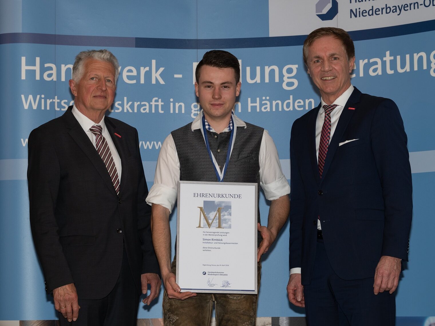 Auf der Bühne erhält Installateur- und Heizungsbauermeister Simon Rimböck eine Urkunde und Medaille von stv. HGF Hans Schmidt und HWK-Vizepräsident Hans Kastl.