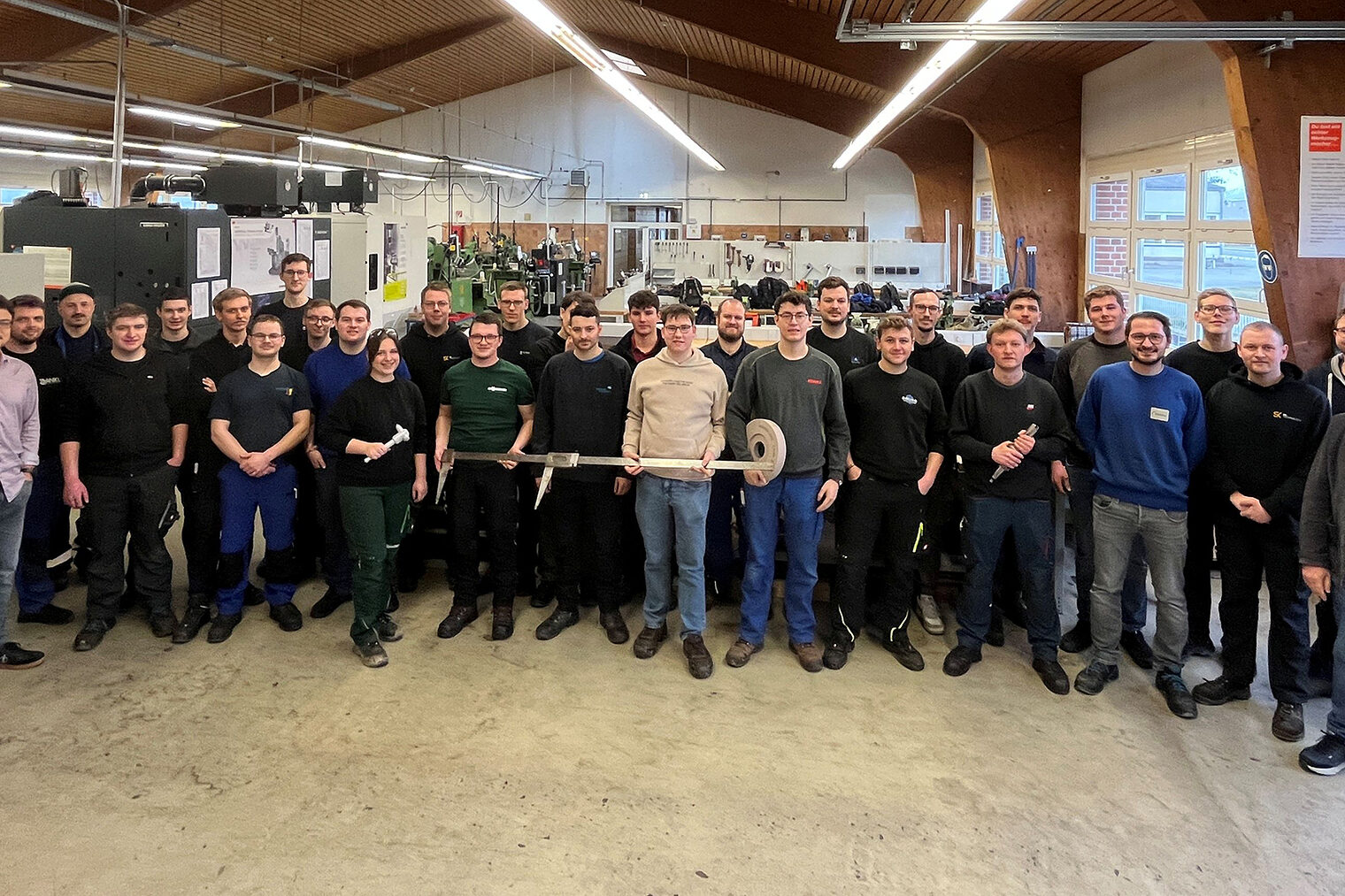 Die Absolventen des Kurses stehen in der der Metallhalle. Kursleiter Wolfgang Meyer und Ausbilder Maximilian Maly sind mit dabei.