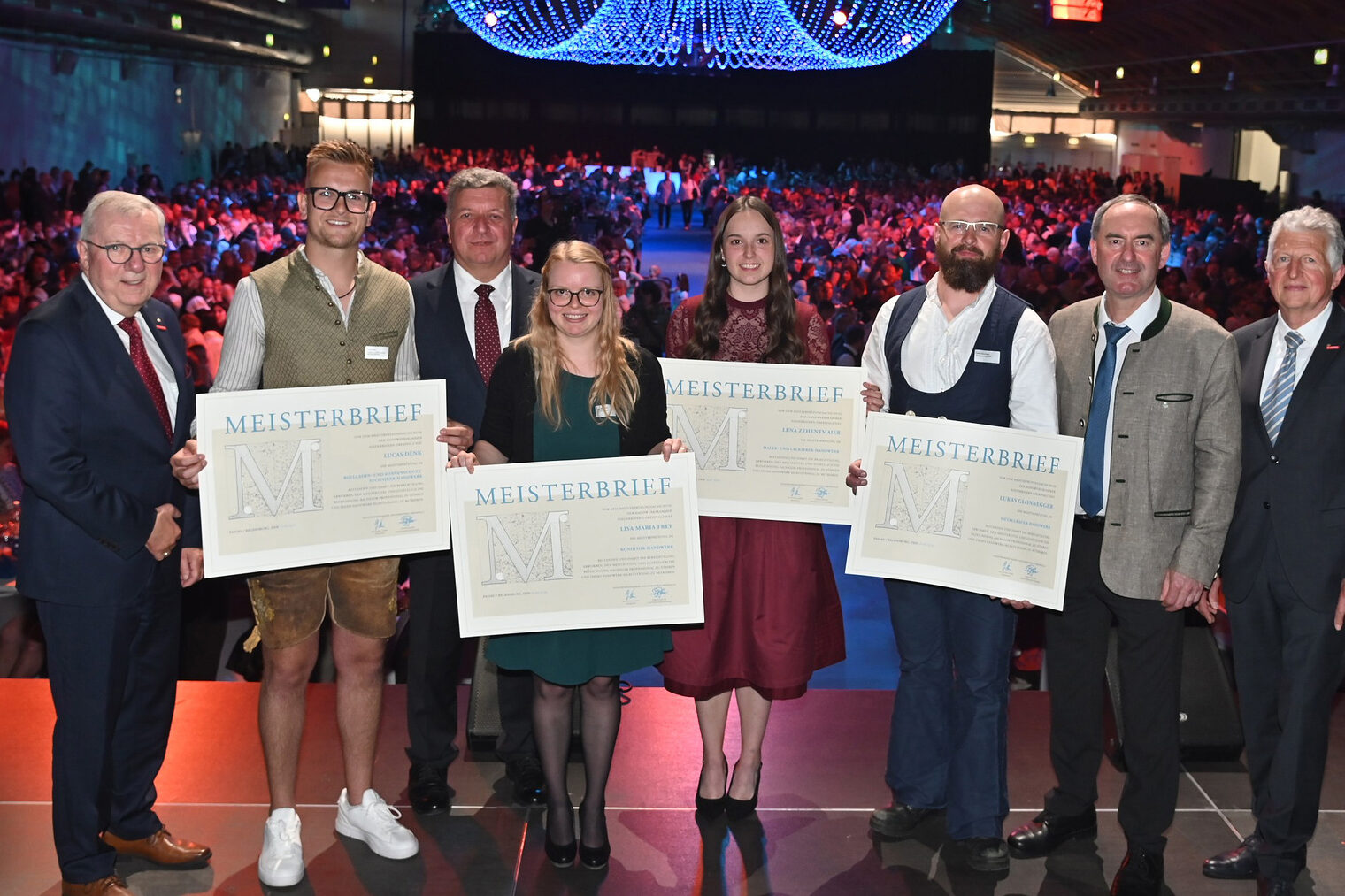 Vier Meister erhalten auf der Bühne ihre Meisterbriefe von Staatsminister Hubert Aiwanger und Hauptgeschäftsführer Jürgen Kilger.