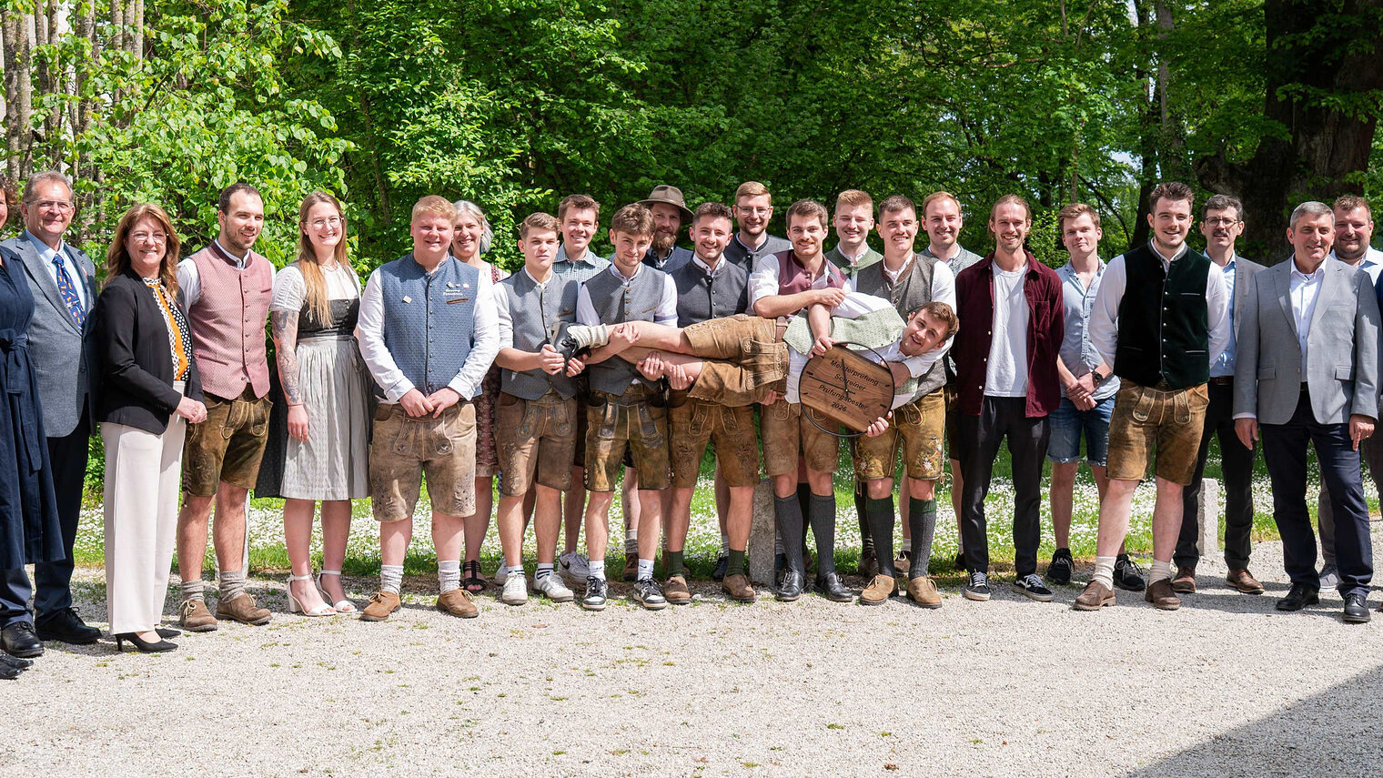 Die erfolgreichen Kursteilnehmer mit den Ehrengästen stellten sich zum Gruppenfoto auf. Mittig hält ein Absolvent eine Uhr in die Höhe.