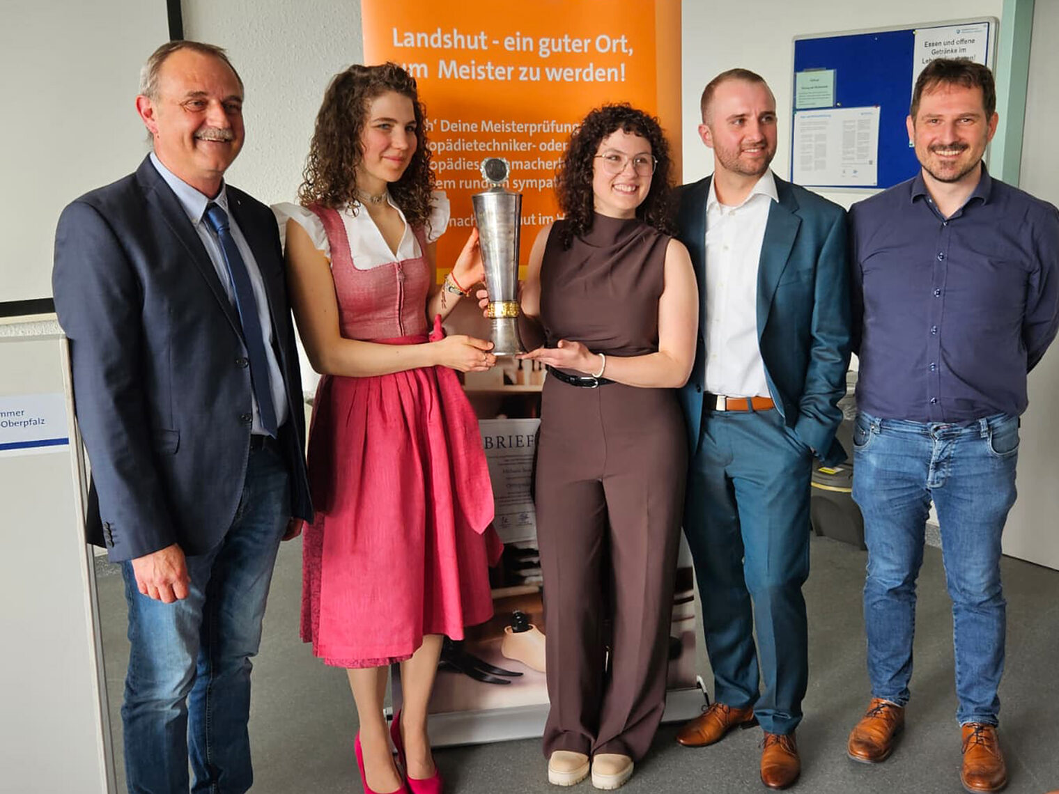 Die zwei Kursbesten halten zusammen den Ehrenpreis in den Händen, daneben der Zweitbeste. 