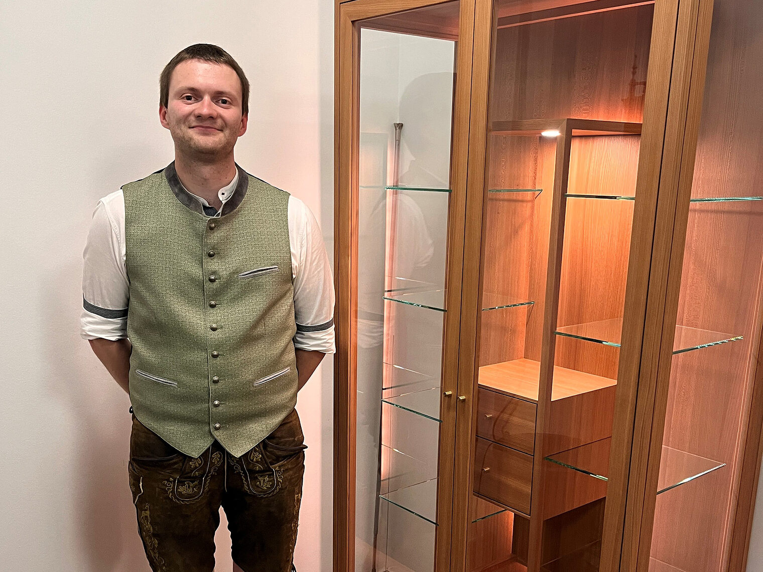 Kursbester Thomas Zirngibl positioniert sich stolz neben seiner fein ausgearbeiteten Büchervitrine. 