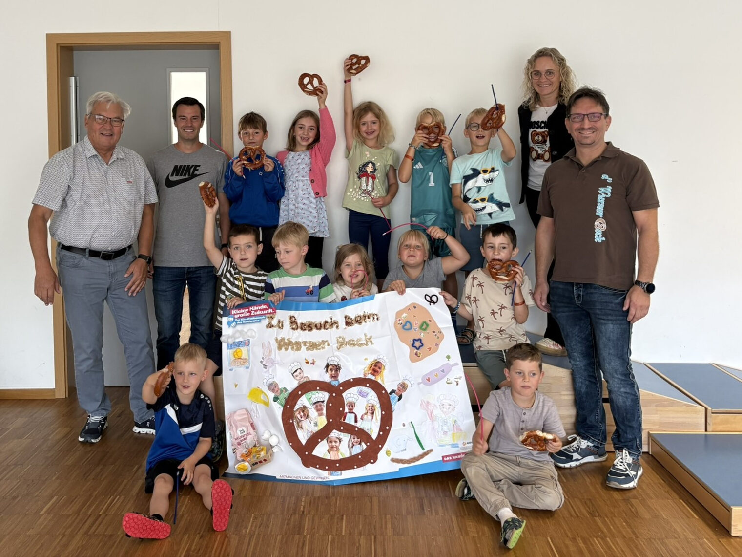 Die Kinder halten ihr Plakat in die Höhe und freuen sich riesig über das Brezen-Frühstück.