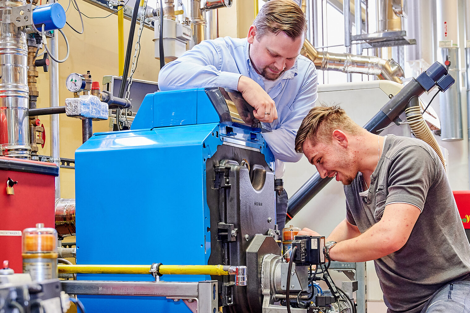 Im Bildungszentrum arbeitet ein Handwerker an einer Pumpe. Der Ausbilder blickt ihm über die Schulter.